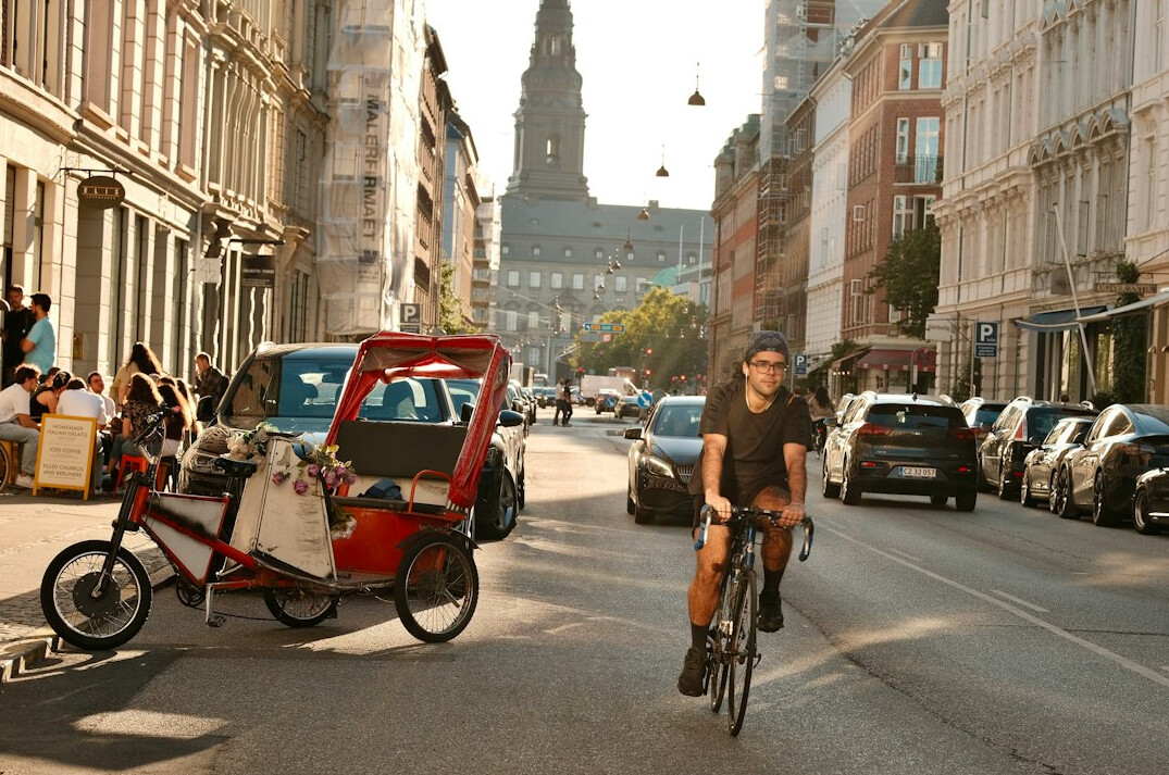 Young Danish man cycling through a city street
