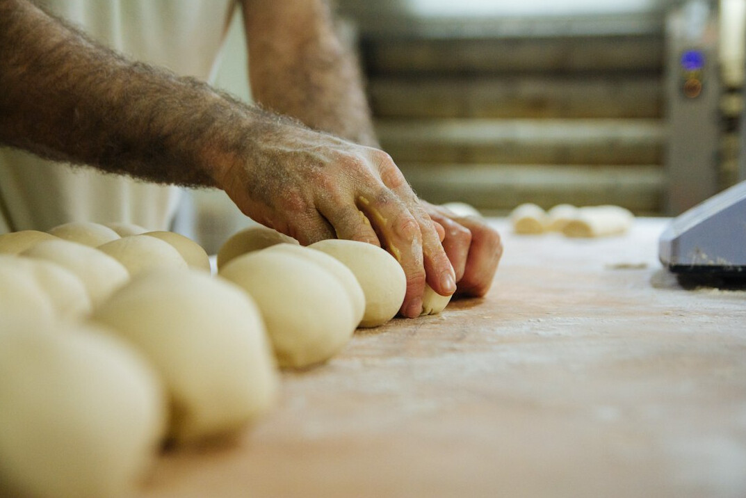 Danish baker shaping rye bread dough in a small bakery